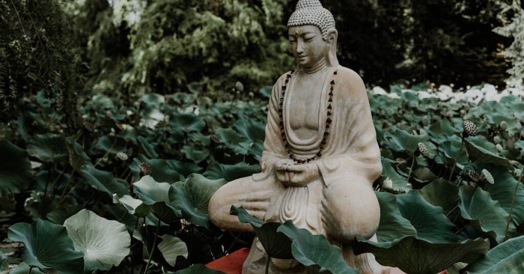 A tranquil Buddha statue surrounded by lush green lotus leaves in a garden, symbolizing peace and serenity.