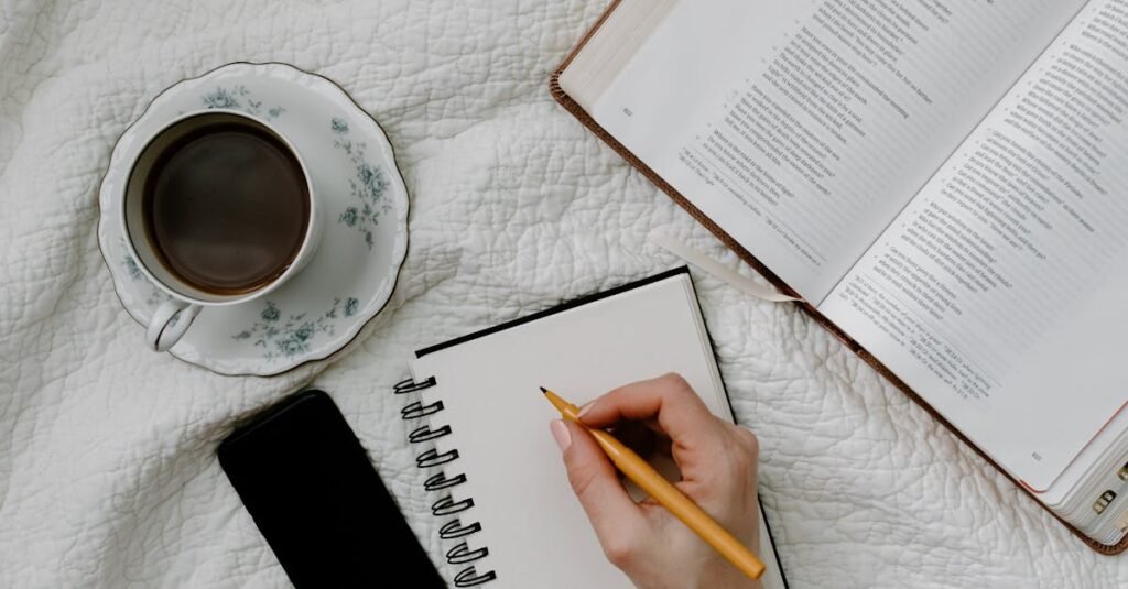 Handwriting on notebook with open book and coffee in bed. Perfect cozy setup for reading or studying.